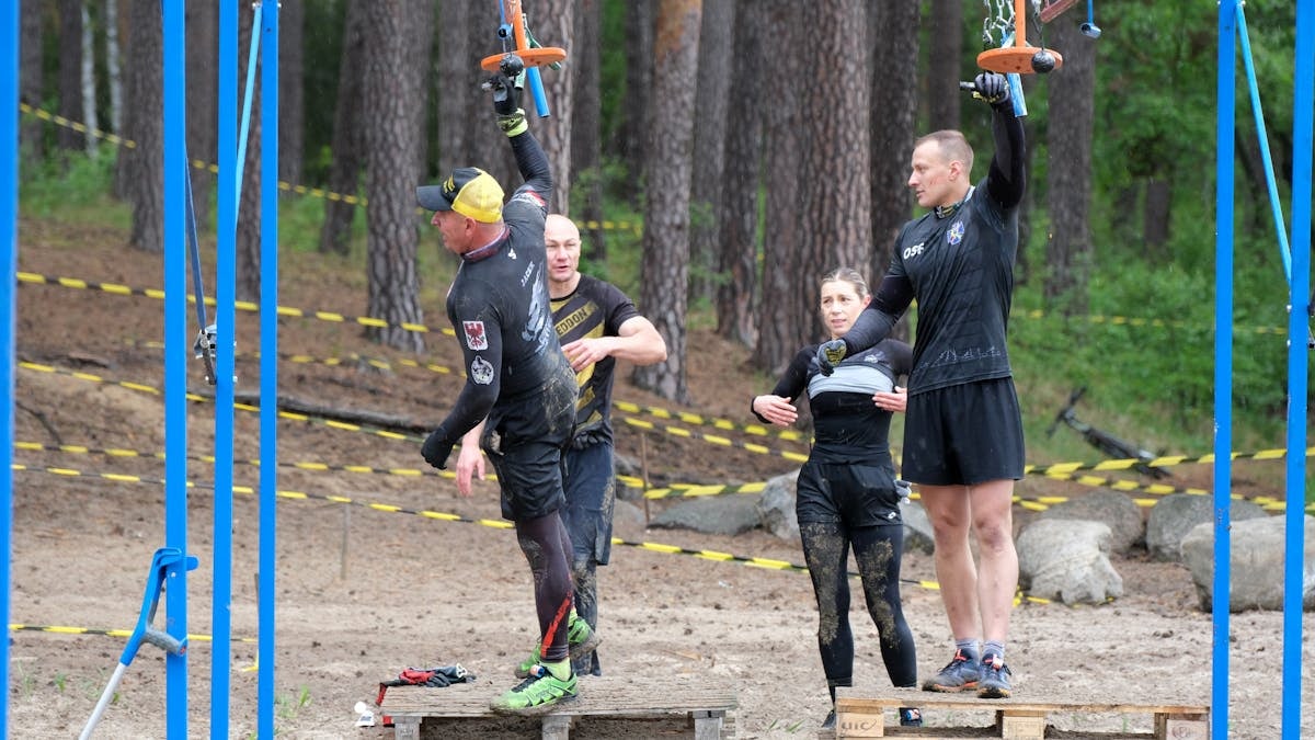 Group of adults navigating an outdoor obstacle course in a forest setting.